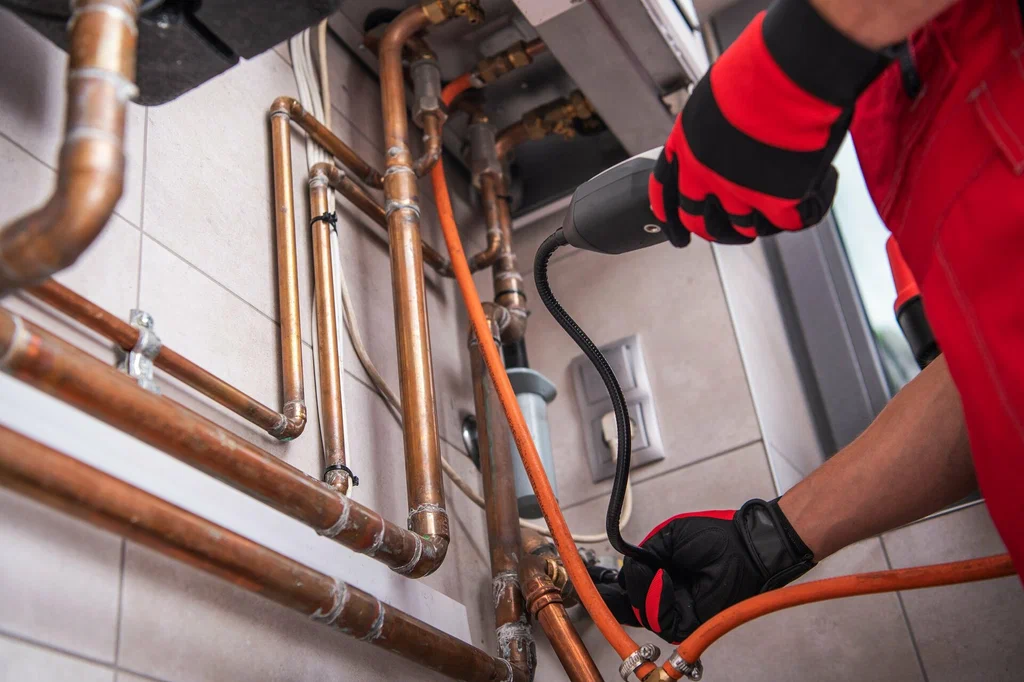 HVAC professional inspecting copper pipes and heating system components