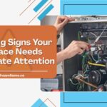 An HVAC technician inspecting the internal wiring and components of an open furnace unit.